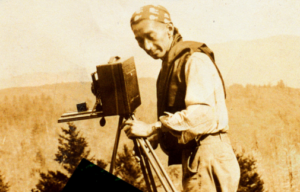 The front cover of George Masa's Wild Vision, a book by Brent Martin. It has a sepia toned photograph of George Masa with a camera.